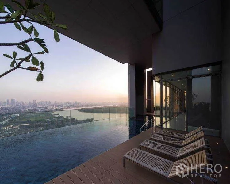 公寓 出租或出售在Bang Rak, Bangkok - 空中无边际泳池，日光躺椅，夕阳下的城市与河景全景。