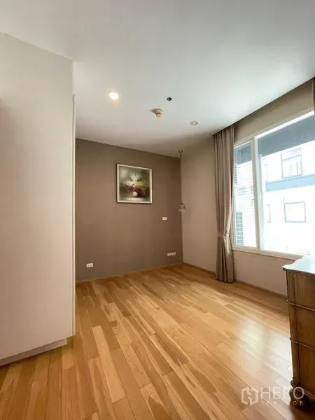 Condominium for rent in Watthana, Bangkok - Bright empty room with hardwood floors, large window and neutral walls.