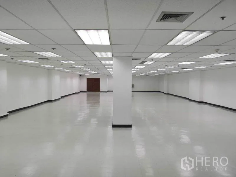 Office Space for rent in Phaya Thai, Bangkok - Deep section of the office leading toward a wooden service door, white walls and overhead lighting.