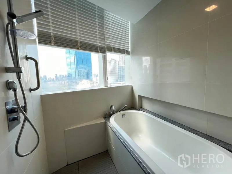 Condominium for rent in Khlong Toei, Bangkok - Bathroom with bathtub by the window offering skyline views.