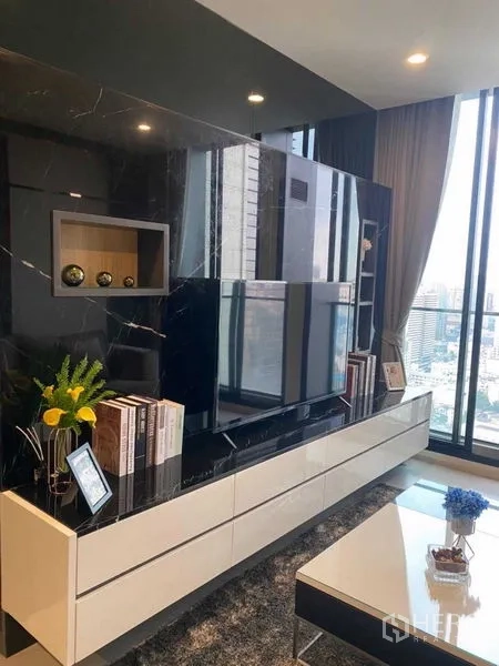 Condominium for sale in Pathum Wan, Bangkok - Living area media wall with black marble panel and white storage cabinet.
