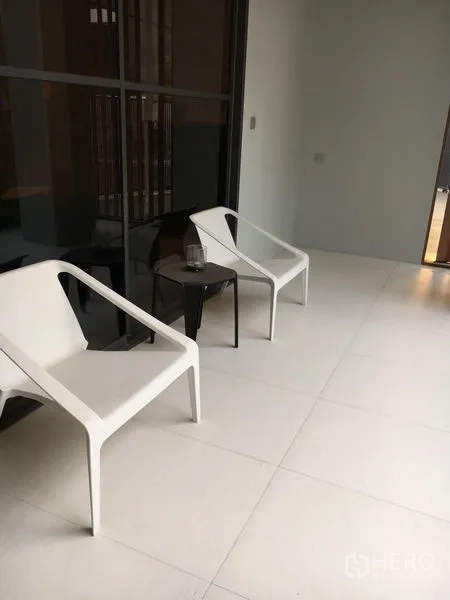 Detached House for rent in Wang Thonglang, Bangkok - Covered terrace with two white lounge chairs and a small side table on light tiles.