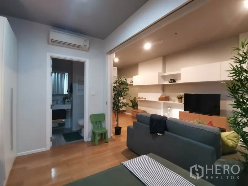 公寓 出租或出售在Watthana, Bangkok - 舒适起居区，面向卫生间入口，带滑动隔断与绿植。