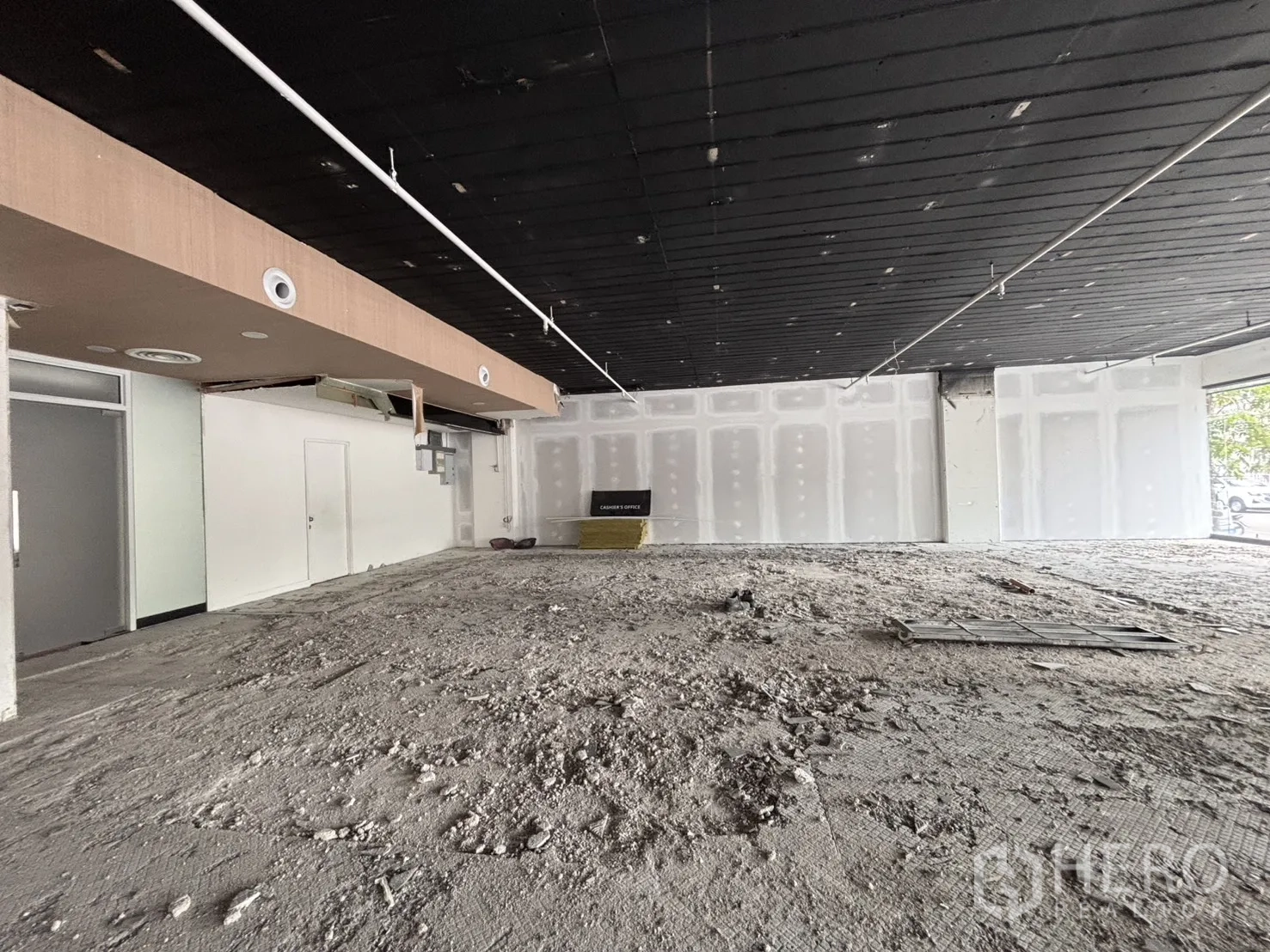 Retail Space for rent in Bang Rak, Bangkok - Wide interior view of unfinished retail area with high black ceiling and a partitioned back room.