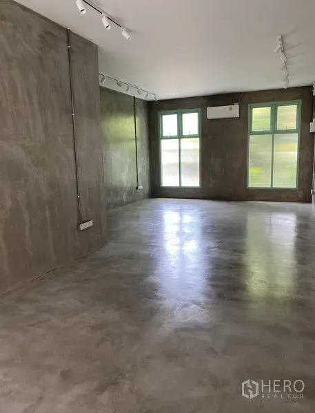 Retail Space for rent in Watthana, Bangkok - Open interior with polished concrete floors, gray plaster walls, large windows and track lighting.