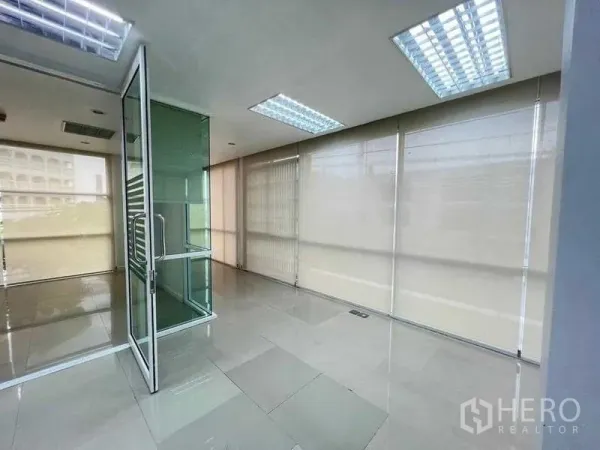 Office Space for rent in Wang Thonglang, Bangkok - Corner office area with floor-to-ceiling windows, roller blinds, and a clear glass door.