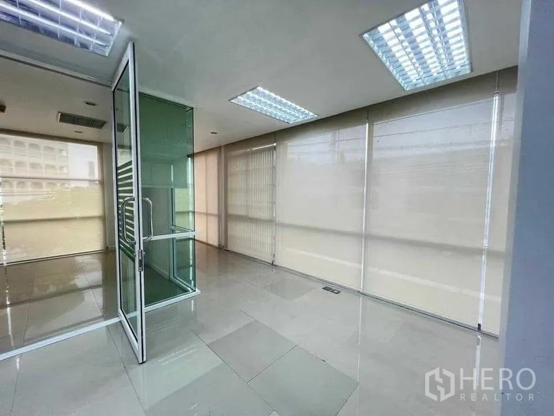 Office Space for rent in Wang Thonglang, Bangkok - Corner office area with floor-to-ceiling windows, roller blinds, and a clear glass door.