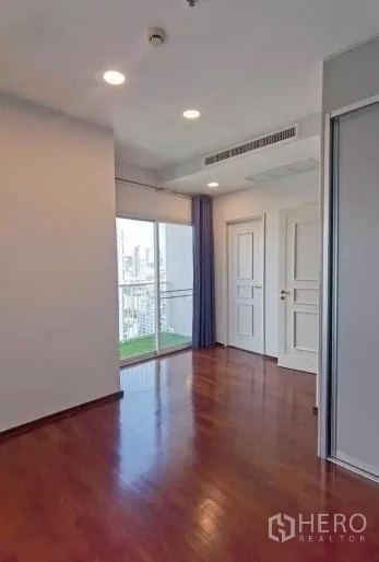 คอนโด ขายในWatthana, Bangkok - ห้องโปร่งพื้นไม้พร้อมไฟดาวน์ไลท์และประตูกระจกบานเลื่อนออกสู่ระเบียงวิวเมือง
