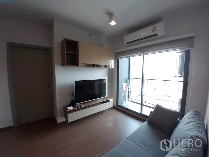 Condominium for rent in Phra Khanong, Bangkok - Cozy living room with sofa, TV console and sliding glass doors opening to a balcony.