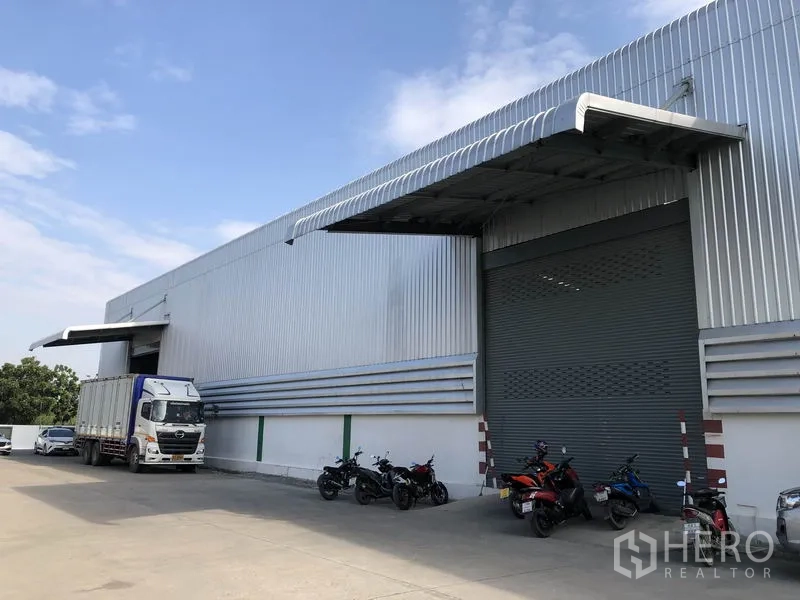 货栈 出租在Pathum Thani - 仓库侧视图，带顶装卸月台、高挑屋顶与宽阔车道，适合拖挂车