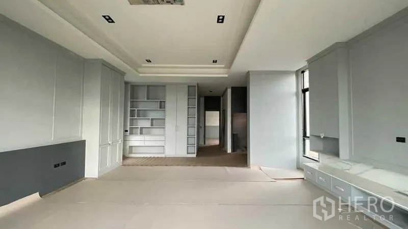 独立式住宅 出售在Mueang Nonthaburi, Nonthaburi - 宽敞客厅，内置书柜与高窗，浅灰色定制柜体。