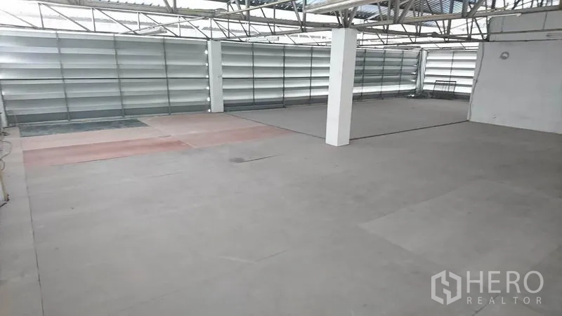 Warehouse for rent in Lak Si, Bangkok - Spacious clear-span storage area with high steel truss roof and louvered ventilation panels.