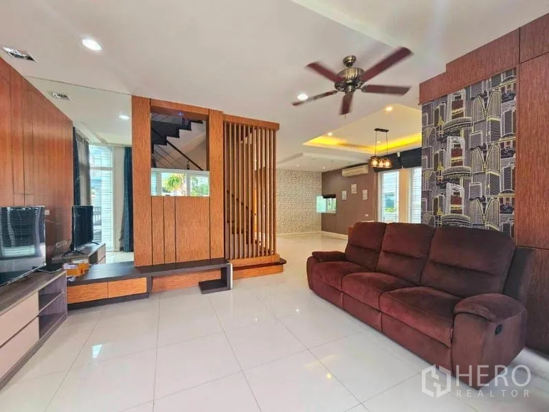 Detached House for rent in Chatuchak, Bangkok - Open-plan living room with plush sofa, ceiling fan and wooden partition wall.
