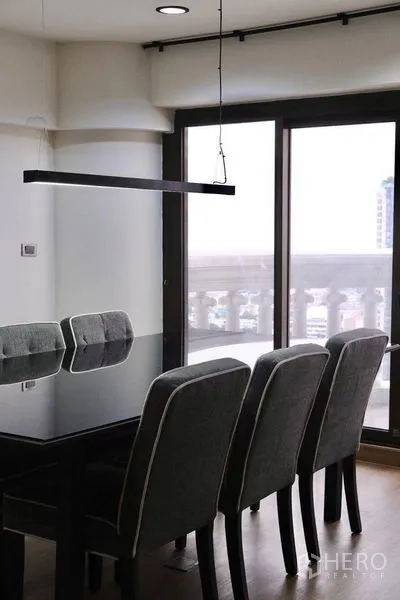 Condominium for rent in Bang Rak, Bangkok - Dining area with glass-top table, four chairs and sliding doors to the balcony.