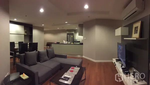 คอนโด ให้เช่าในHuai Khwang, Bangkok - ห้องนั่งเล่นแบบโอเพ่นแพลน โซฟาสีเทา ผนังทีวี และพื้นไม้โทนอุ่น