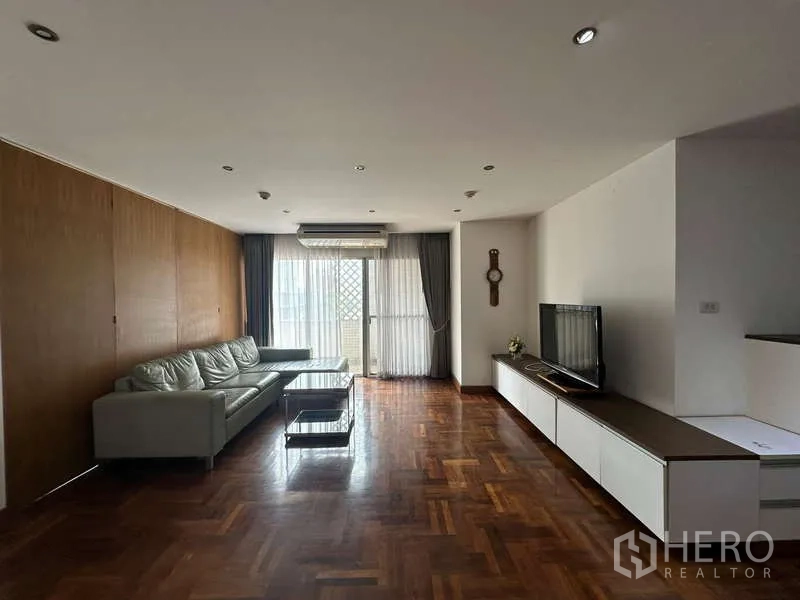 公寓 出租在Watthana, Bangkok - 宽敞起居区，配沙发、电视墙柜与拼花地板。