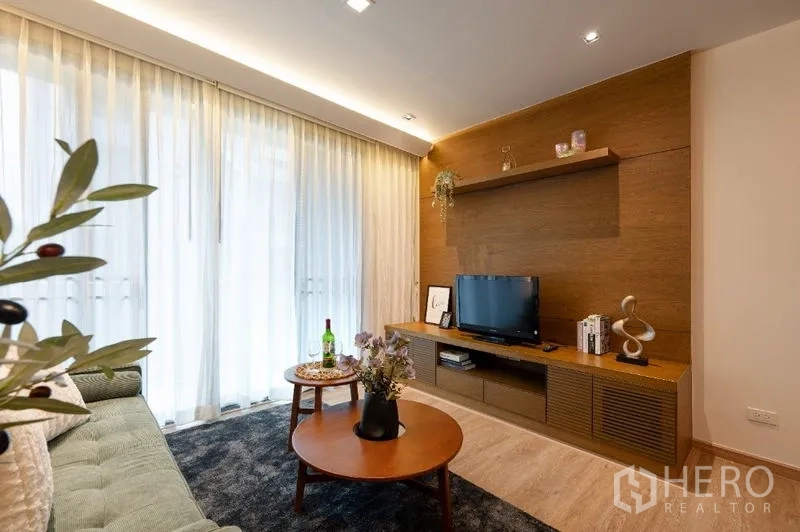 Condominium for sale - Living area with sheer curtains, TV console and warm wood accent wall.