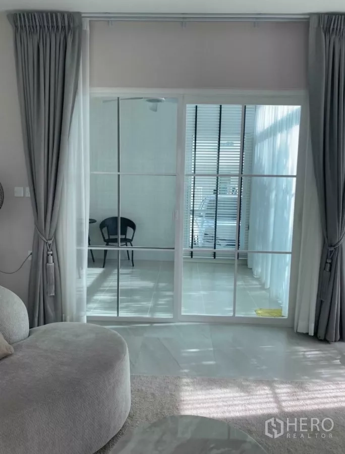 独立式住宅 出租在Bang Phli, Samut Prakan - 客厅后方的玻璃房/日光室，白色格栅推拉门。