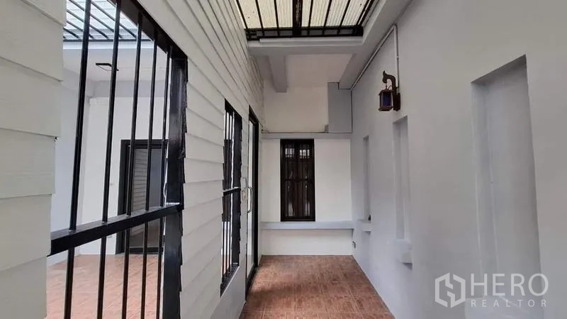 联排别墅 出租或出售在Chatuchak, Bangkok - 带顶侧露台走廊，白墙与黑色防护栏