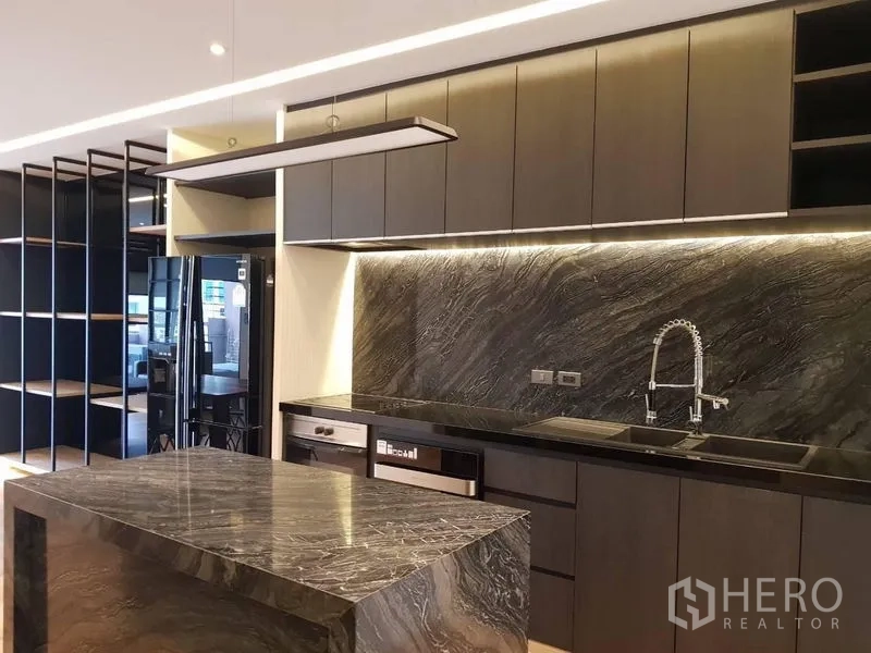 Condominium for rent in Bang Rak, Bangkok - Modern open kitchen with dark stone island, full-height cabinets and soft LED lighting.