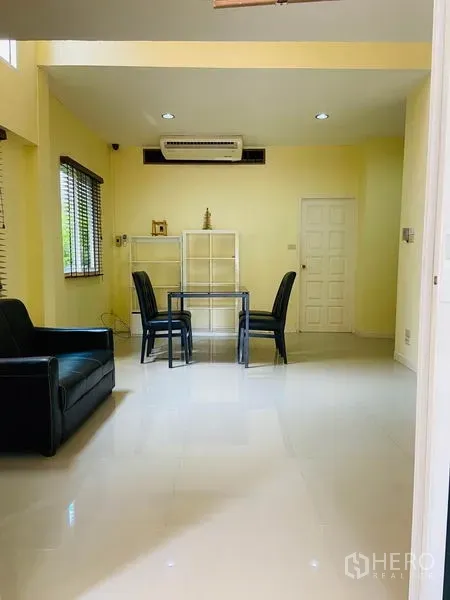 Detached House for rent in Watthana, Bangkok - Bright living area with sofa, small dining set, glossy floors and built-in air conditioner.