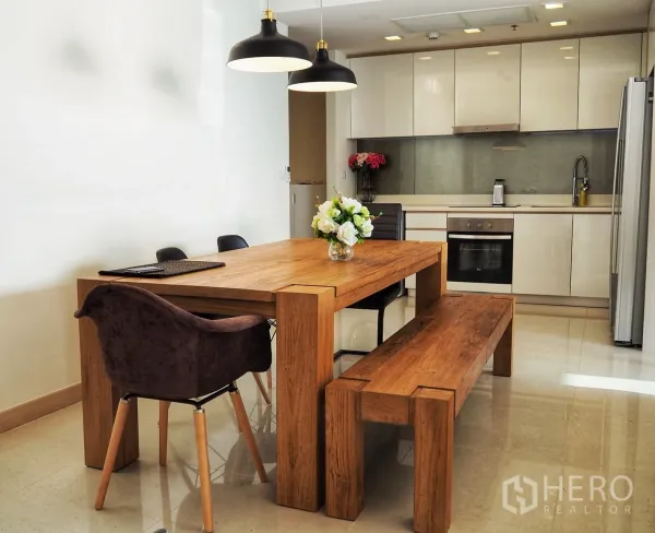 Condominium for rent in Bang Lamung, Chon Buri - Modern kitchen with glossy cabinets, built-in oven, large fridge and a solid wood dining table with bench seating.