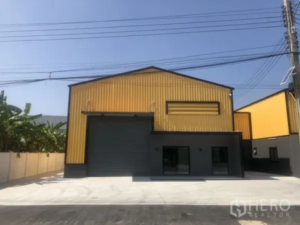 Factory for rent in Bang Yai, Nonthaburi - Front view of a factory unit showing a high roller shutter, glass-fronted office and ample parking space.