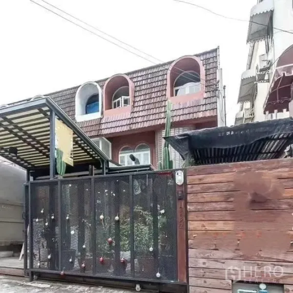 Home Office for rent in Bang Rak, Bangkok - Street view of gated townhouse-style home office with metal fence and arched upper windows.