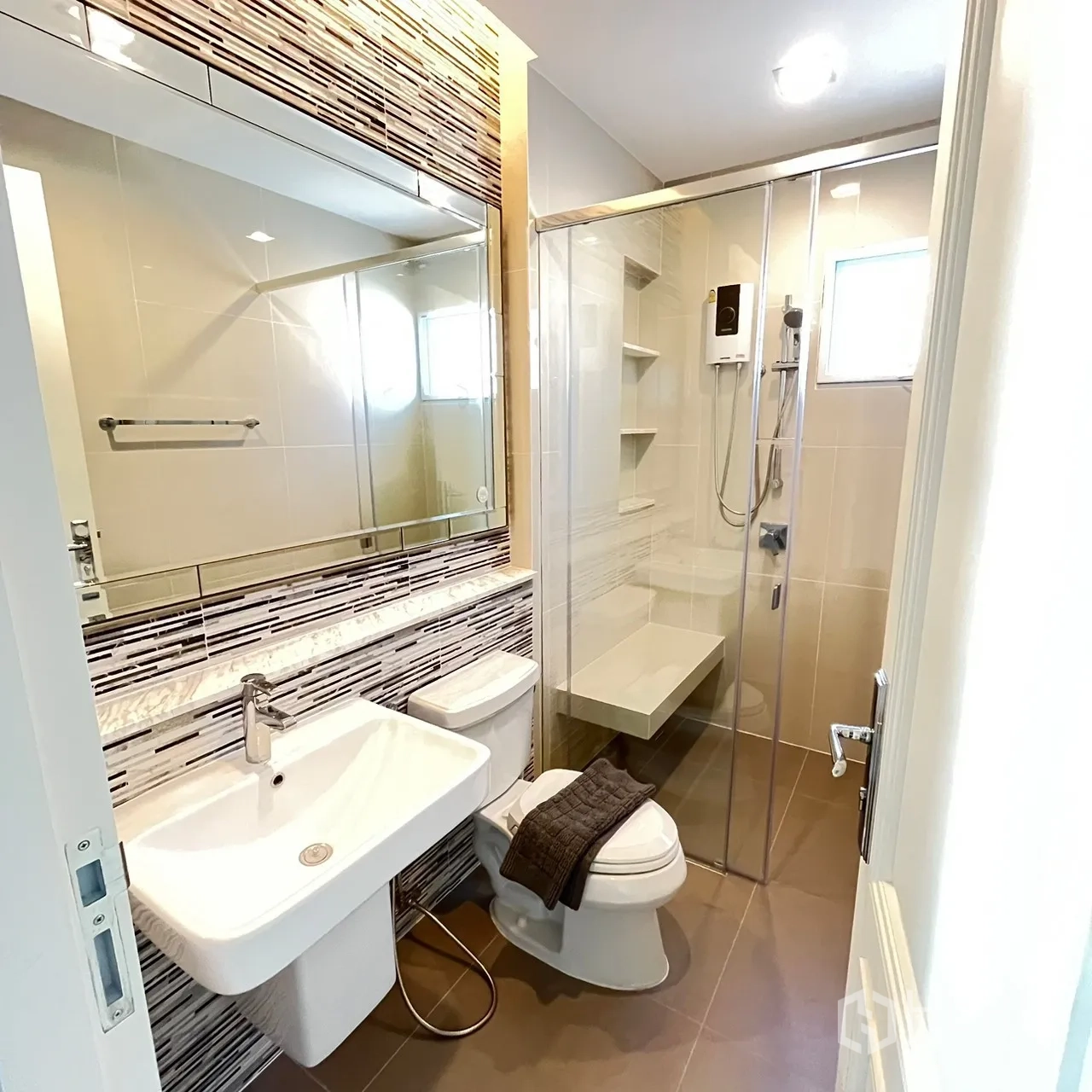 Detached House for rent or sale in Bang Khen, Bangkok - Guest bathroom with glass shower enclosure and large mirror.