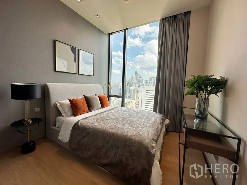 公寓 出租在Pathum Wan, Bangkok - 卧室配软包床，落地窗外是城市天际线景观。