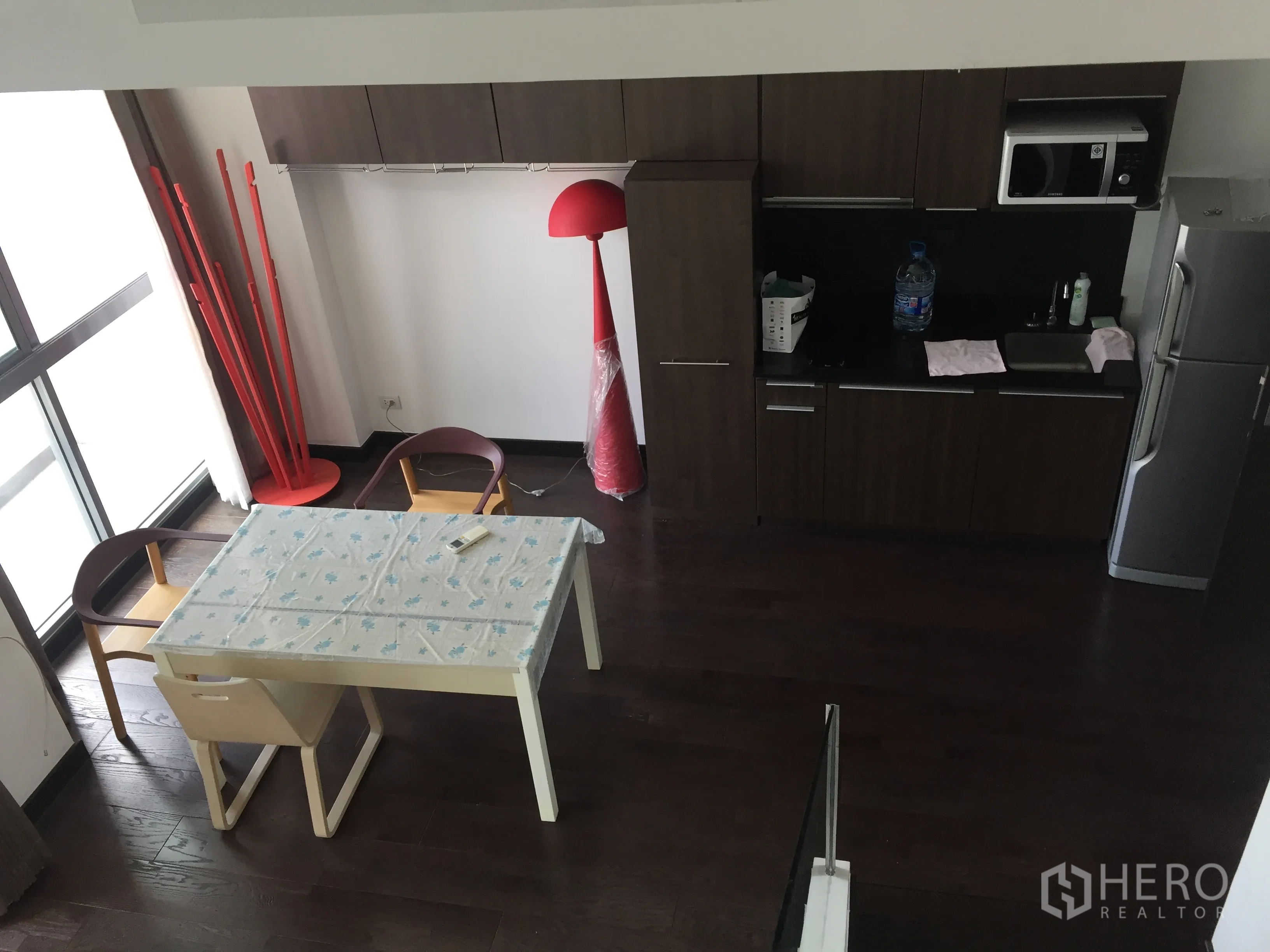 公寓 出租在Ratchathewi, Bangkok - 紧凑厨房，深色橱柜、微波炉与冰箱，旁有临窗餐桌。