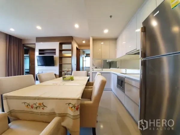 Condominium for rent in Bang Rak, Bangkok - Bright kitchen with built-in cabinets, stainless-steel fridge, and dining area under recessed lighting.