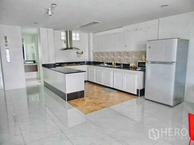 Home Office for rent or sale in Din Daeng, Bangkok - Spacious kitchen with white cabinets, island cooktop, tiled floors and stainless refrigerator.