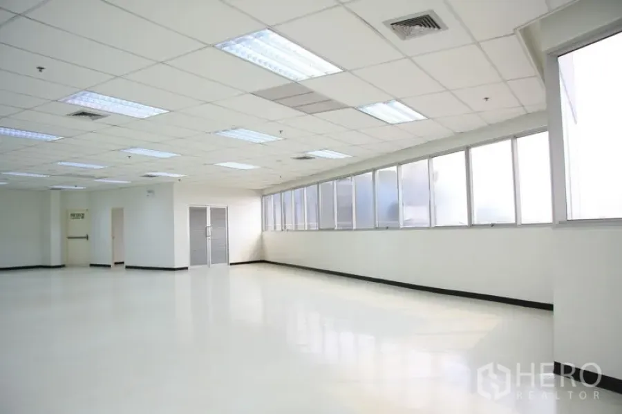办公空间 出租在Chatuchak, Bangkok - 转角办公室，长窗采光充足，旁边设有紧急出口。