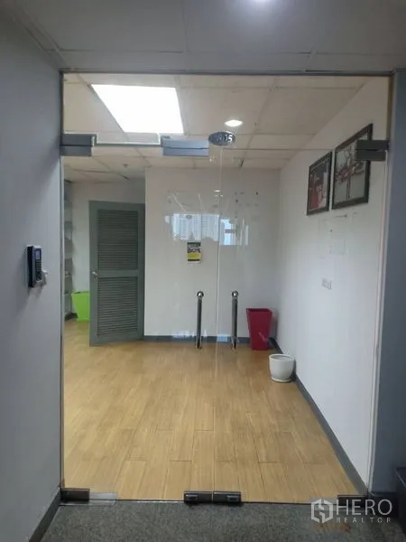 Office Space for rent - View through glass entry door into clean office lobby with wooden floors, white walls and recessed lighting.