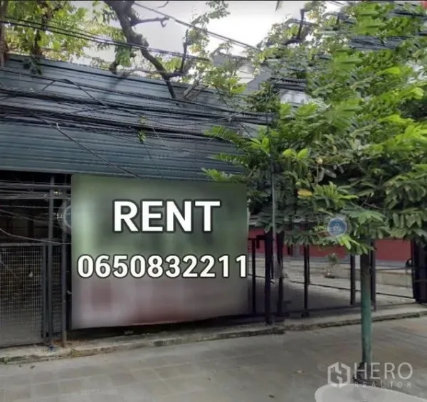 คลังสินค้า ให้เช่าในKhlong Toei, Bangkok - ด้านหน้าโกดังมีต้นไม้ให้ร่มเงา ป้ายให้เช่า และประตูรั้วติดทางเท้า