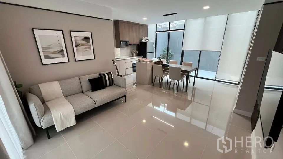 Townhouse for rent or sale in Bang Phli, Samut Prakan - Open‑plan living and dining area with sofa, table and fitted kitchen.