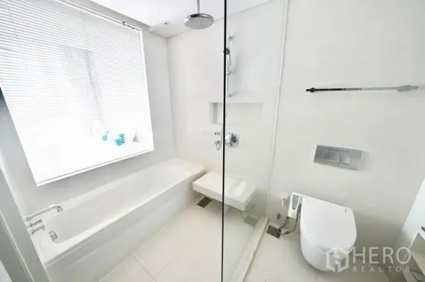 Condominium for rent or sale in Watthana, Bangkok - Bright white bathroom with bathtub, glass rain shower and modern bidet toilet in a Thonglor condo.