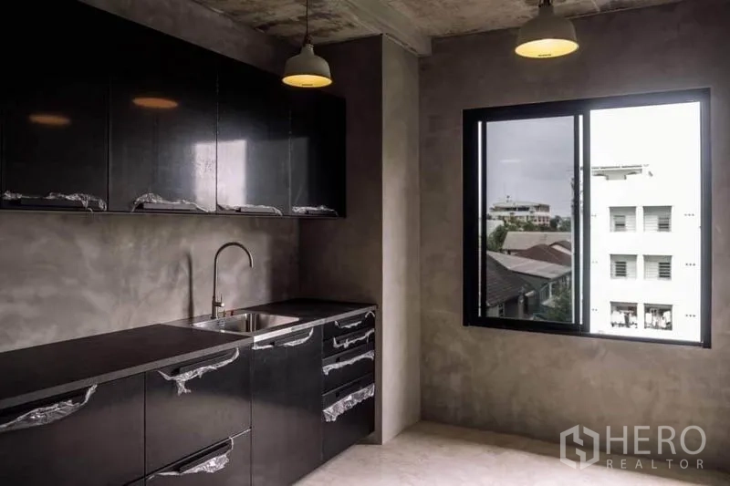 Home Office for rent or sale in Lak Si, Bangkok - Second pantry featuring sleek black cabinets, sink and pendant lights.