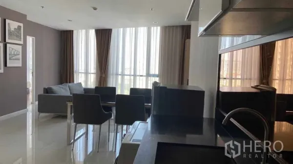 公寓 出租在Watthana, Bangkok - 从厨房望向客厅，落地窗采光充足，餐桌与窗帘一览无余。