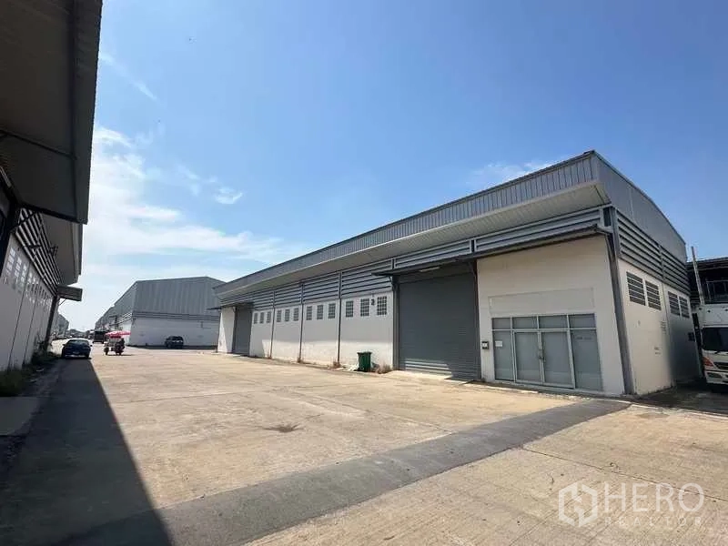 货栈 出租在Bang Bua Thong, Nonthaburi - 仓库外立面设有大型卷闸门与宽敞的装卸区，可进挂车。
