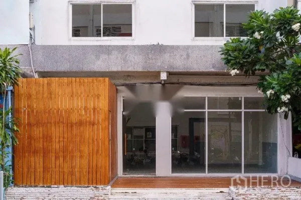 Home Office for rent in Khlong Toei, Bangkok - Street-facing facade with floor-to-ceiling glass doors and a warm wooden privacy screen at the entrance.