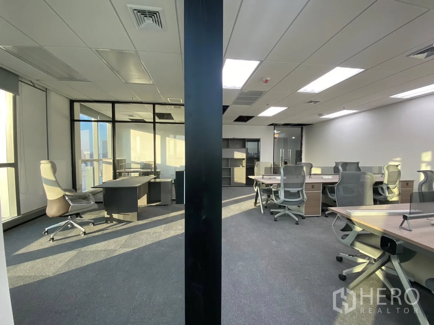 Office Space for rent in Huai Khwang, Bangkok - Wide office layout showing collaborative desks and a glass executive room under recessed lighting.
