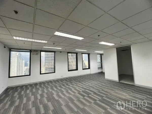 Office Space for rent in Khlong Toei, Bangkok - Open-plan office with grey carpet tiles, drop ceiling and skyline views through multiple windows.