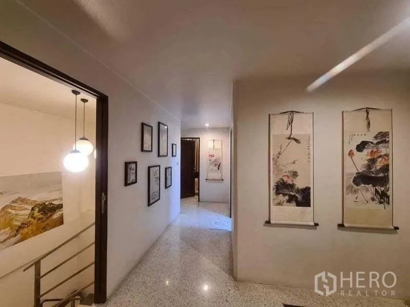 Townhouse for rent or sale in Bang Kho Laem, Bangkok - Upstairs hallway with framed artwork and pendant lights beside the staircase.