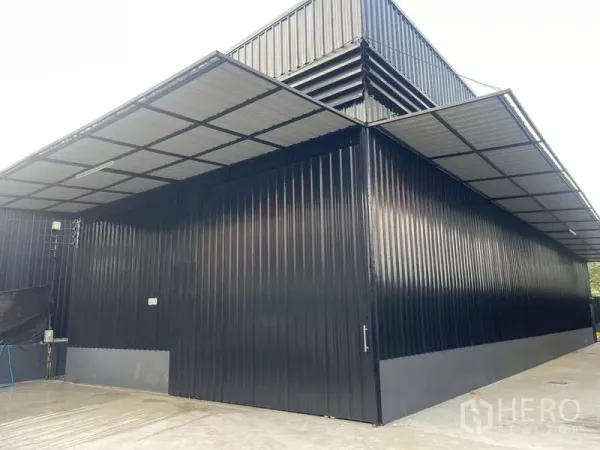 Warehouse for rent in Wang Thonglang, Bangkok - Modern black metal warehouse exterior with large doors, canopy roof, and concrete apron.