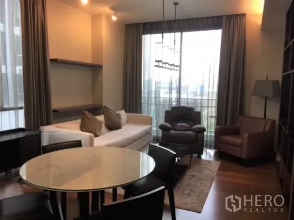公寓 出租或出售在Watthana, Bangkok - 通罗公寓客厅采光充足，配沙发与扶手椅，阳台可见城市景观。