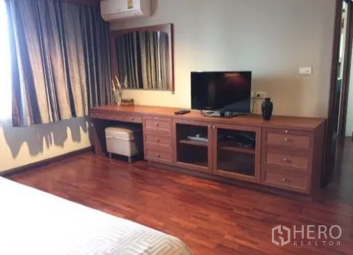 Condominium for rent or sale in Watthana, Bangkok - Bedroom corner with TV console, dressing table and window curtains.