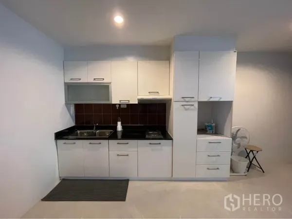 公寓 出租或出售在Watthana, Bangkok - 白色整体小厨房，黑色台面，双水槽与灶台储物柜。
