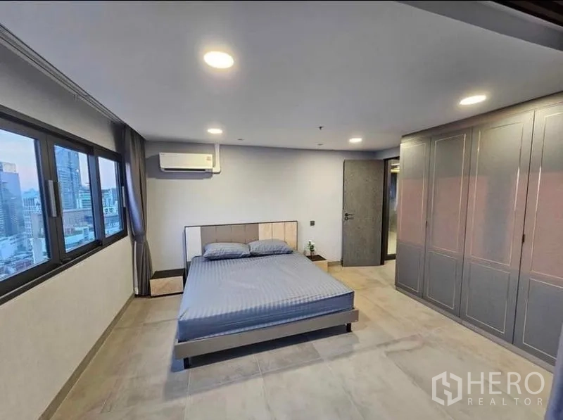 Condominium for rent or sale - Spacious bedroom with wall-to-wall wardrobes and city views.